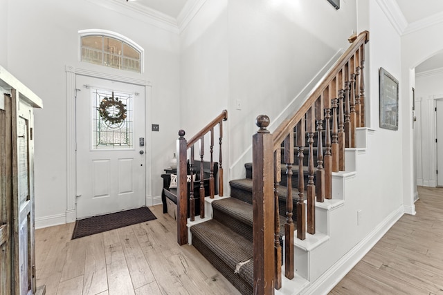 foyer with crown molding, light wood finished floors, and stairs