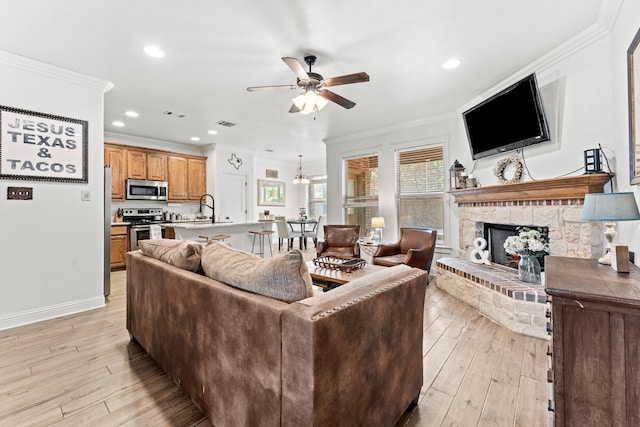 living room with ornamental molding, light wood finished floors, a ceiling fan, and recessed lighting