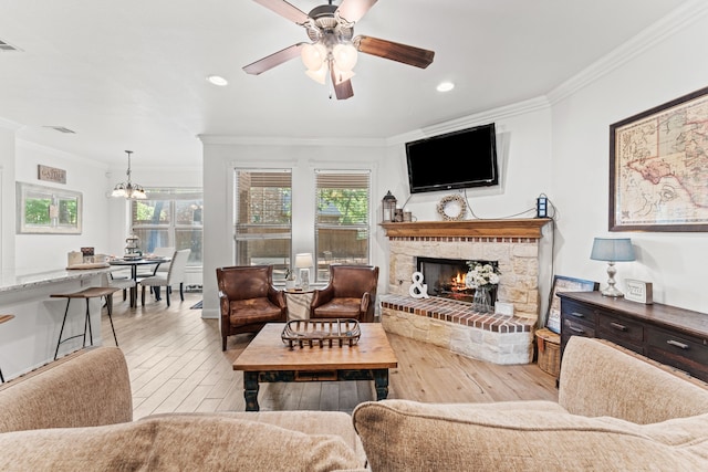living area featuring hardwood / wood-style floors, ornamental molding, ceiling fan with notable chandelier, and a lit fireplace