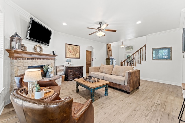 living room featuring arched walkways, stairway, ceiling fan, baseboards, and light wood-type flooring