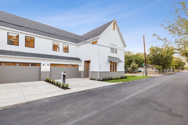 view of front of house featuring driveway, a garage, board and batten siding, and roof with shingles