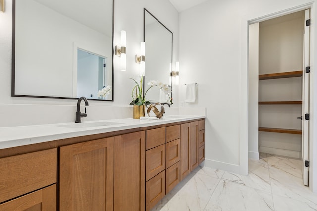full bath featuring double vanity, baseboards, marble finish floor, and a sink
