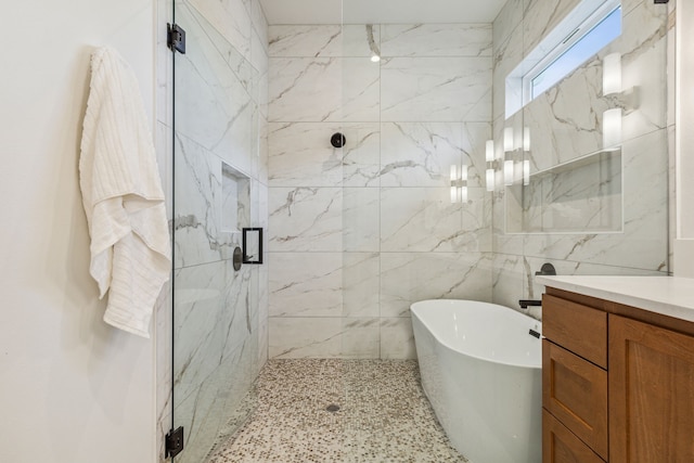 full bathroom featuring a soaking tub, a marble finish shower, and vanity