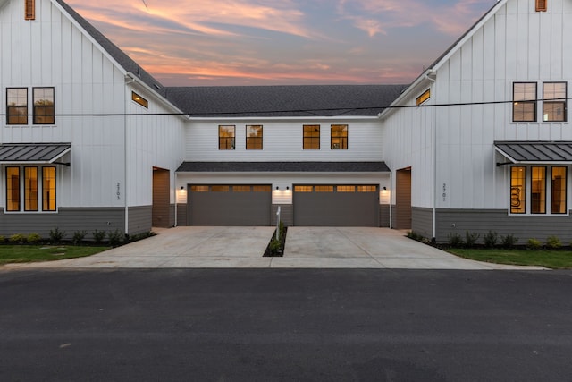 modern farmhouse style home with a standing seam roof, board and batten siding, and an attached garage