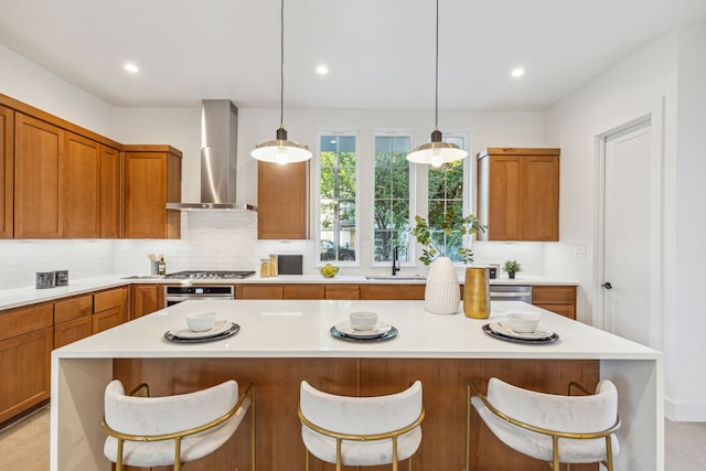 kitchen featuring brown cabinetry, wall chimney exhaust hood, light countertops, and decorative backsplash