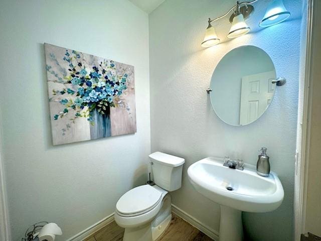 bathroom featuring toilet, wood finished floors, and baseboards
