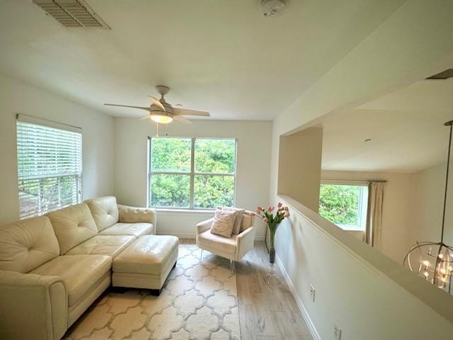 living room with a ceiling fan, visible vents, baseboards, and light wood-style floors