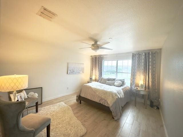 bedroom featuring visible vents, light wood-style floors, a ceiling fan, and baseboards
