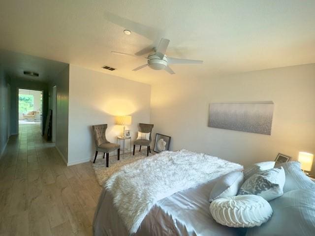bedroom featuring wood finished floors, ceiling fan, visible vents, and baseboards