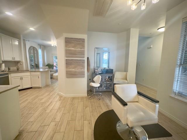 kitchen with white cabinetry, light wood-style floors, and baseboards