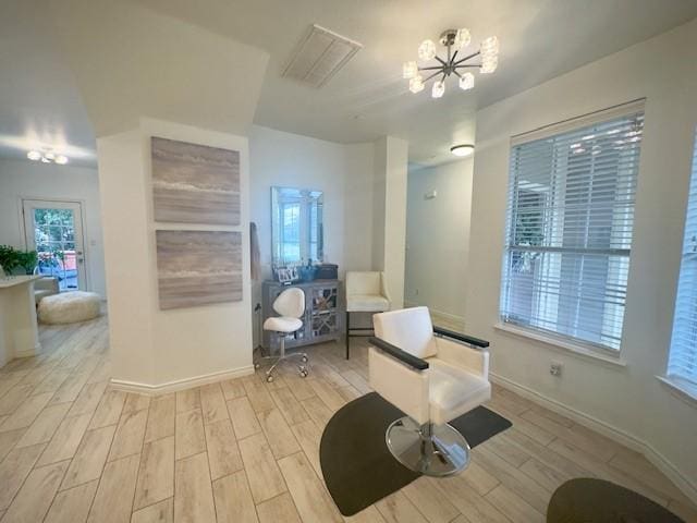 interior space featuring a notable chandelier, light wood-style floors, visible vents, and baseboards