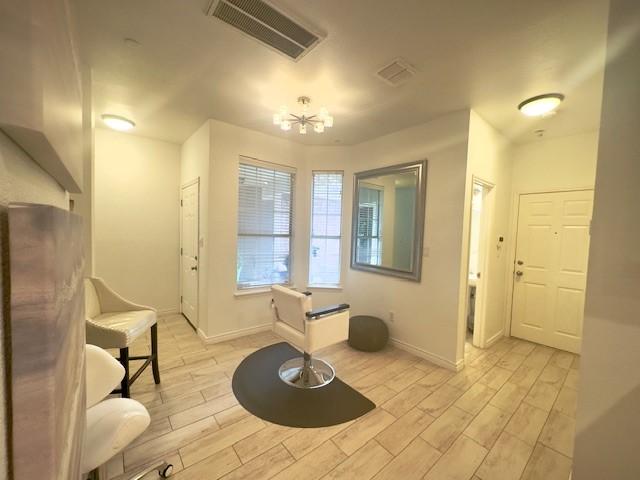 interior space featuring baseboards, visible vents, a chandelier, and light wood-style flooring