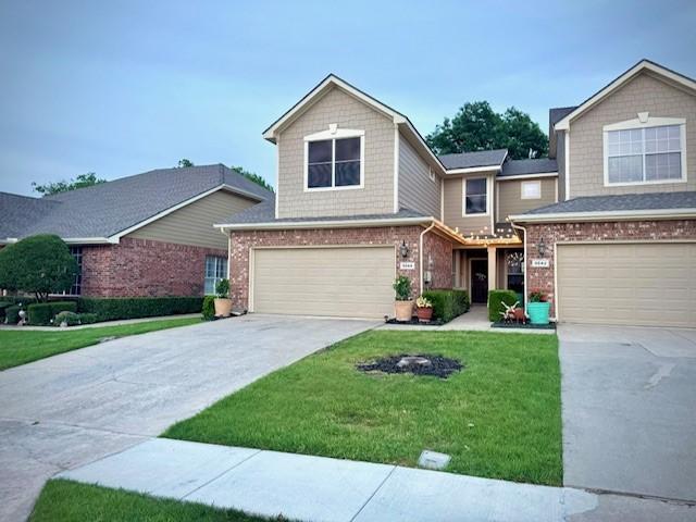 view of front of property with concrete driveway, a front yard, an attached garage, and brick siding