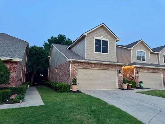 townhome / multi-family property featuring a front yard, driveway, an attached garage, and brick siding