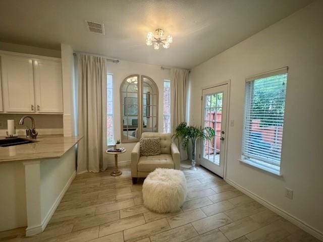 sitting room with a healthy amount of sunlight, visible vents, an inviting chandelier, and baseboards