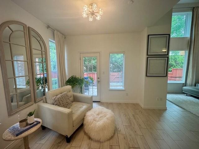 living area with baseboards, a chandelier, and light wood-style floors