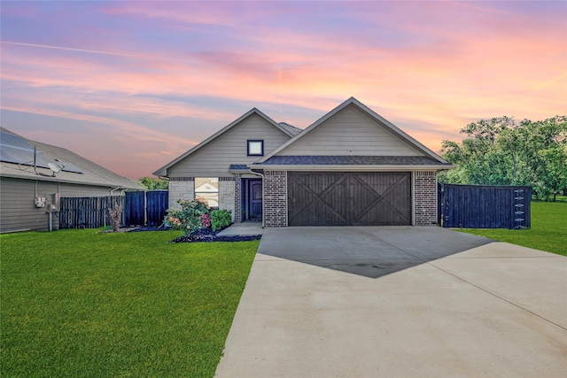 view of front of house featuring fence, an attached garage, a front lawn, brick siding, and driveway