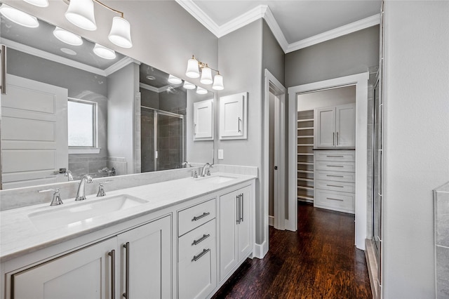 bathroom featuring double vanity, a stall shower, wood finished floors, a sink, and ornamental molding