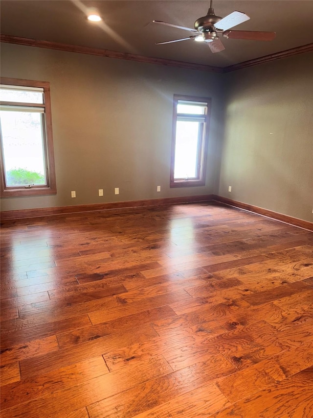 spare room with crown molding, ceiling fan, baseboards, and wood finished floors