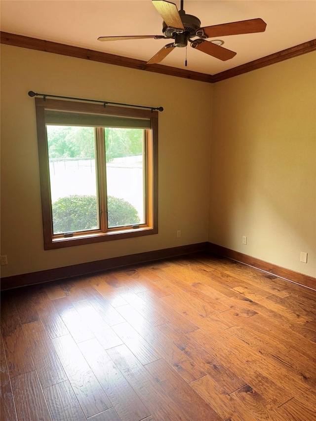 unfurnished room featuring a ceiling fan, baseboards, ornamental molding, and wood finished floors