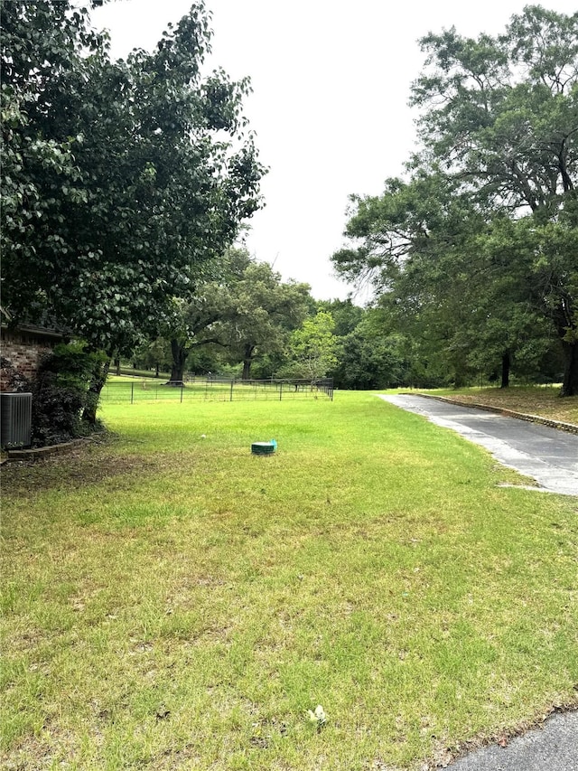 view of yard with central AC unit and fence