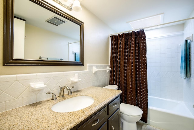 2403 Leslie St, Denton, TX 76205 - bathroom featuring toilet, vanity, shower / bath combo with shower curtain, tile walls, and wainscoting
