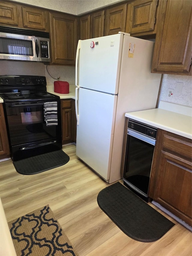 kitchen with stainless steel microwave, light countertops, wall oven, freestanding refrigerator, and black range with electric cooktop