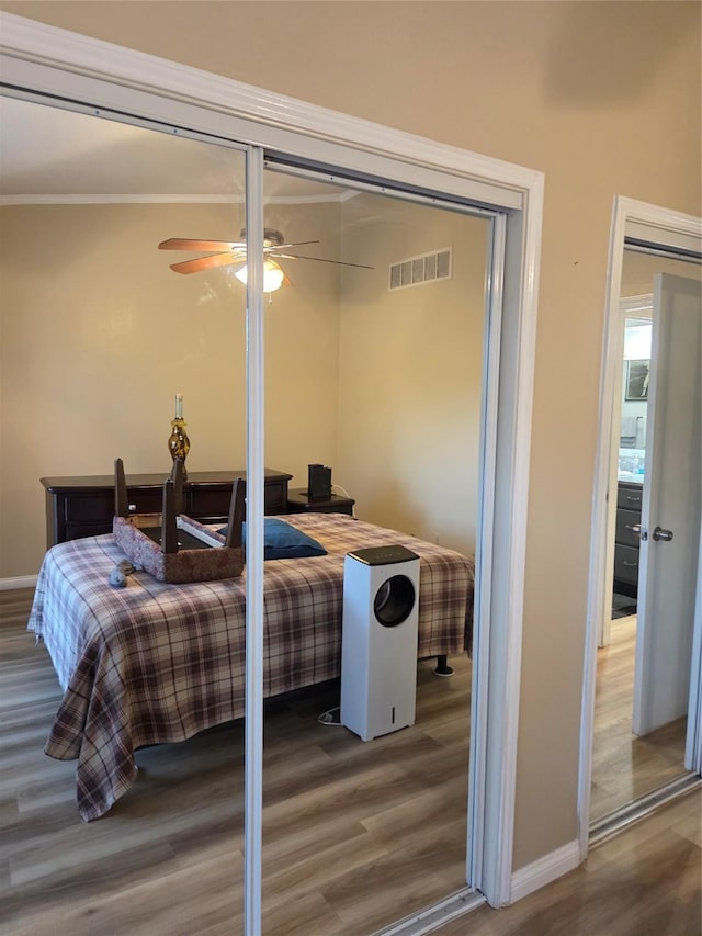 bedroom with visible vents, wood finished floors, and baseboards