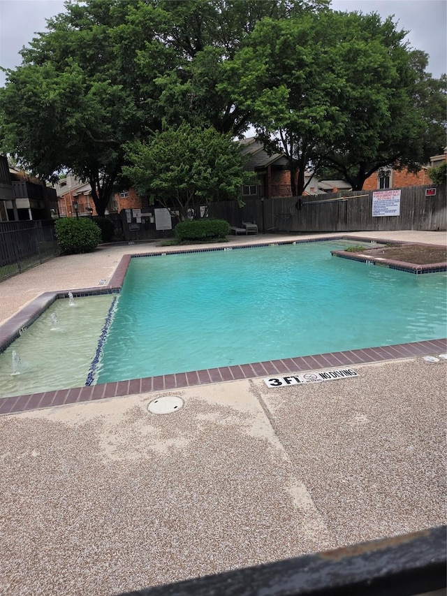 pool with a patio and fence