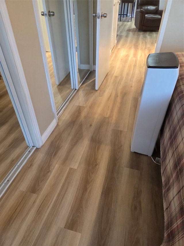 corridor featuring light wood-style flooring and baseboards