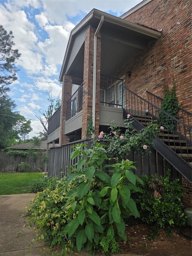 view of home's exterior with fence, stairs, and brick siding