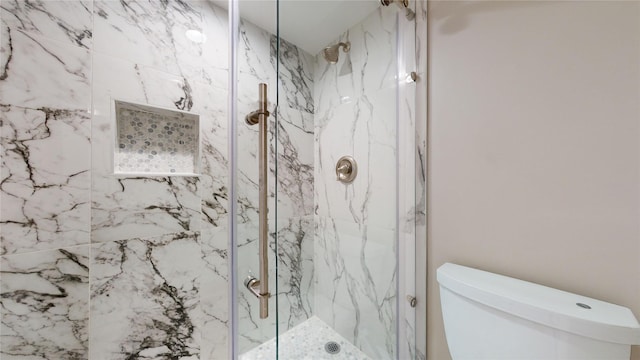 bathroom with toilet and a marble finish shower