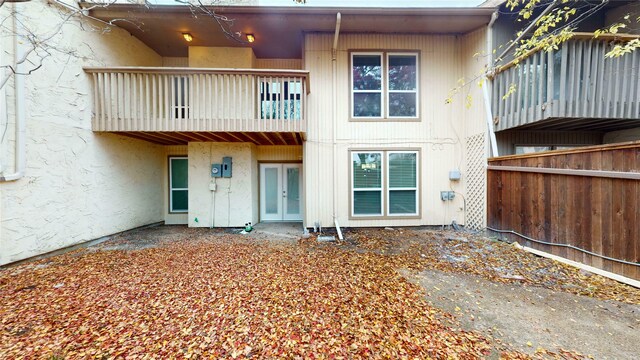 back of property featuring fence, a balcony, french doors, and stucco siding