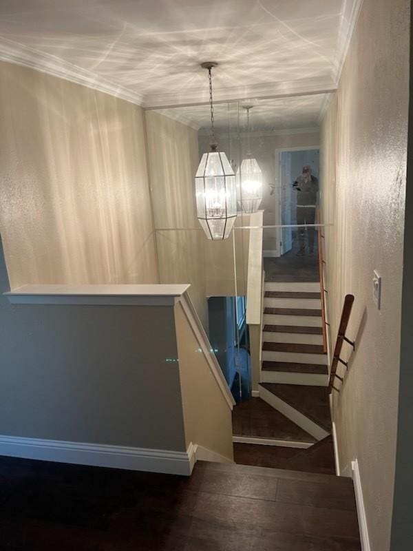 staircase with wood finished floors, a chandelier, crown molding, and baseboards