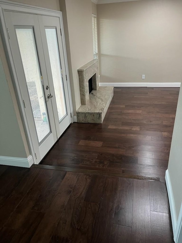 unfurnished living room featuring a high end fireplace, french doors, dark wood finished floors, and baseboards