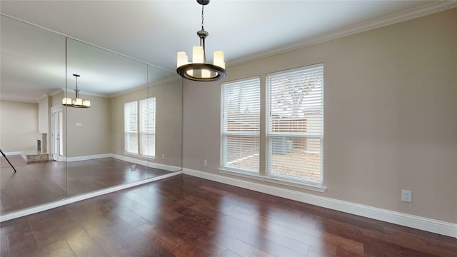 spare room with ornamental molding, hardwood / wood-style floors, a notable chandelier, and baseboards