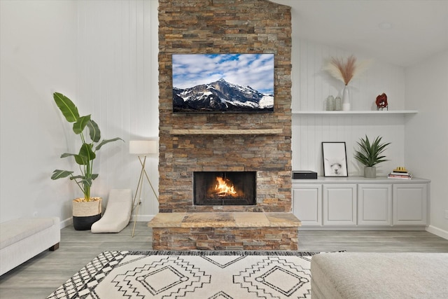 living area with baseboards, wood finished floors, and a fireplace