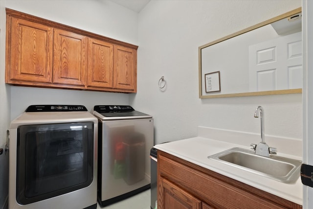 clothes washing area with a sink, cabinet space, and washing machine and clothes dryer