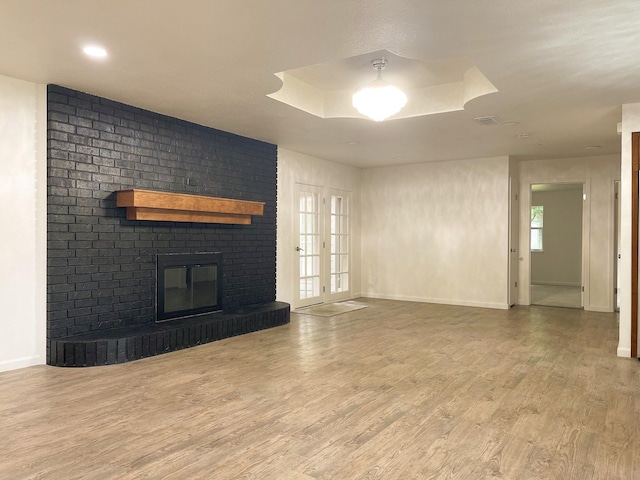 unfurnished living room with baseboards, wood finished floors, and a fireplace