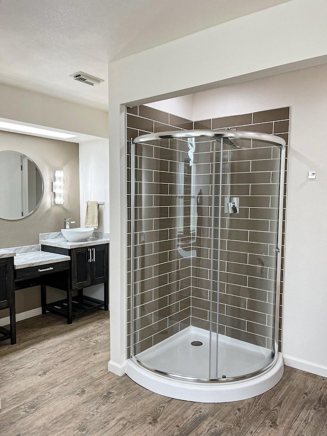 full bathroom featuring visible vents, a stall shower, baseboards, wood finished floors, and vanity