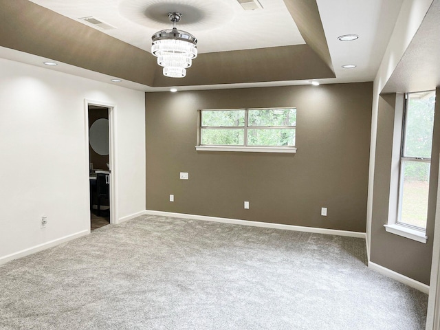 spare room with carpet, visible vents, and a tray ceiling