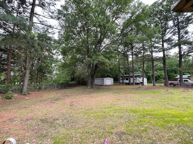 view of yard featuring an outbuilding, a shed, and fence