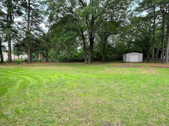 view of yard featuring a garage, fence, an outdoor structure, and a storage shed