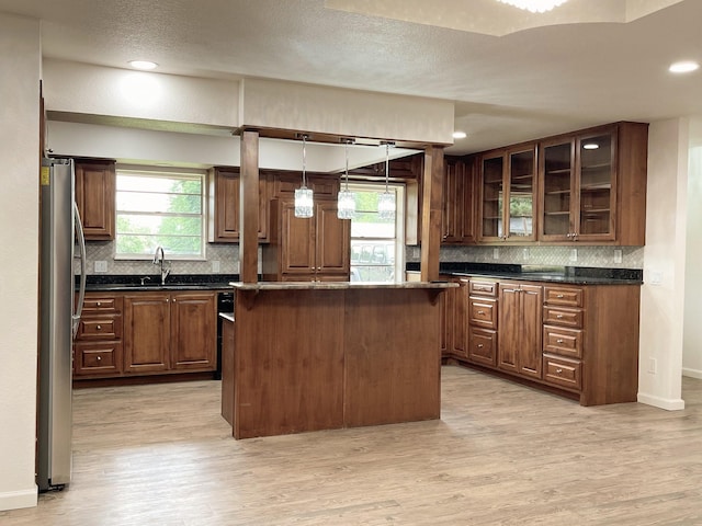 kitchen with light wood-type flooring, a sink, freestanding refrigerator, and tasteful backsplash