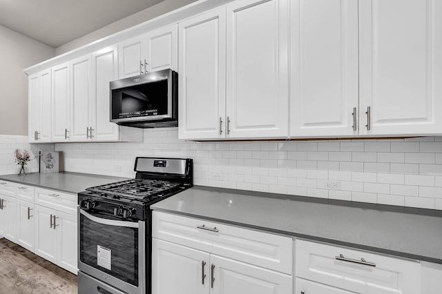 kitchen with light wood-style flooring, backsplash, white cabinets, and appliances with stainless steel finishes