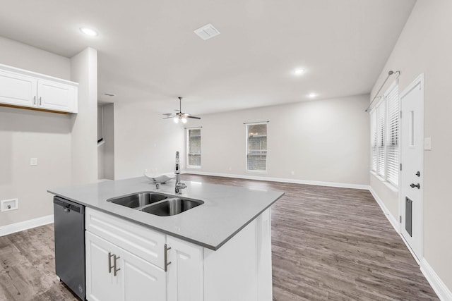 kitchen with recessed lighting, wood finished floors, stainless steel dishwasher, white cabinets, and a sink