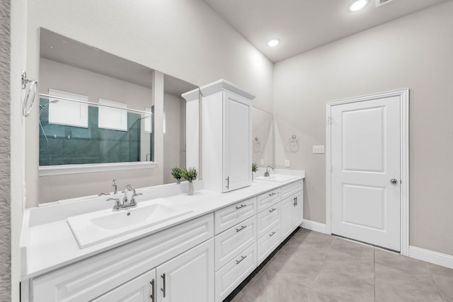 full bathroom with double vanity, a shower stall, baseboards, and a sink