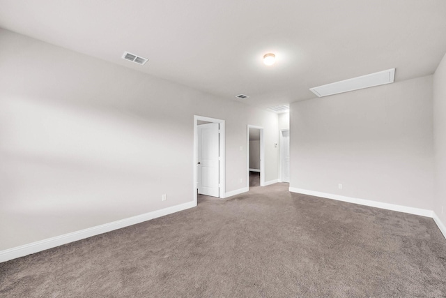 unfurnished room with baseboards, visible vents, attic access, and carpet
