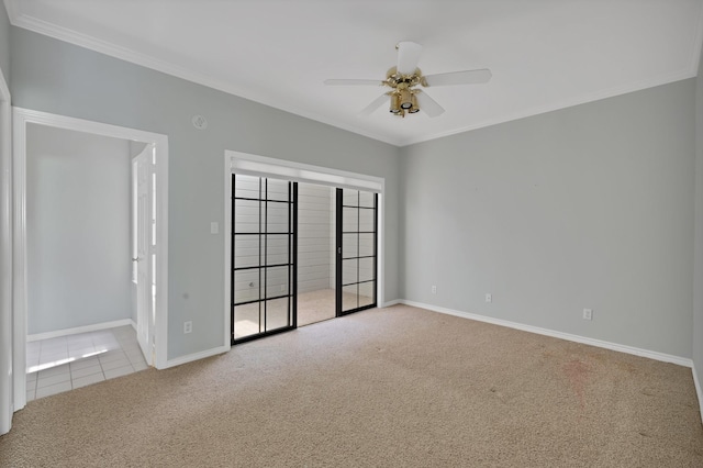 tiled spare room featuring ornamental molding, ceiling fan, carpet floors, and baseboards