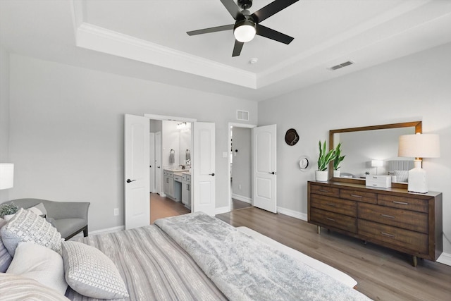 1146 Berrydale Dr, Northlake, TX 76226 - bedroom featuring a raised ceiling, wood finished floors, ornamental molding, a ceiling fan, and connected bathroom